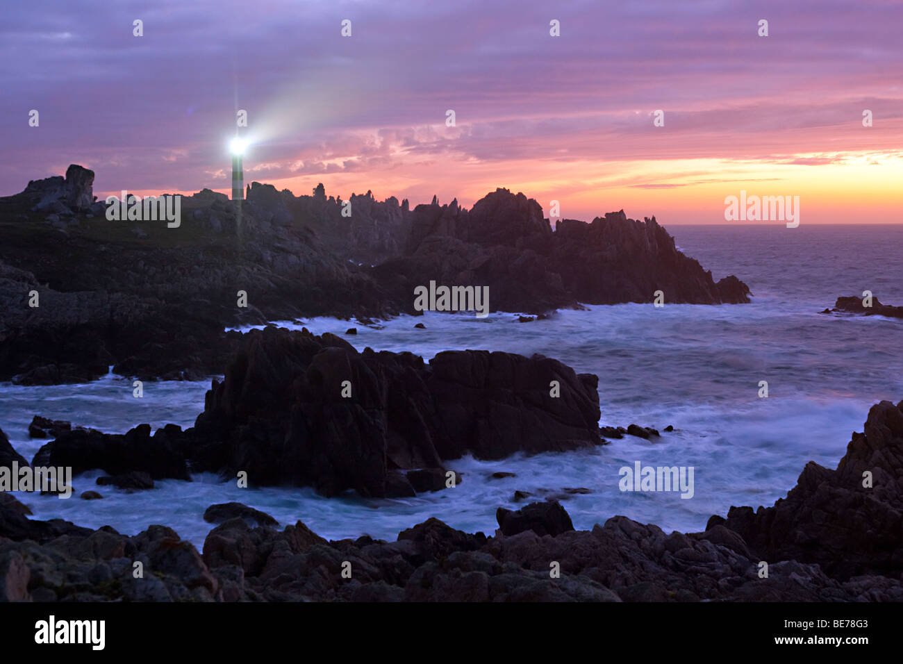 ouessant island rocky coastline at dusk with creac'h lighthouse lighted, brittany, finistere, france Stock Photo