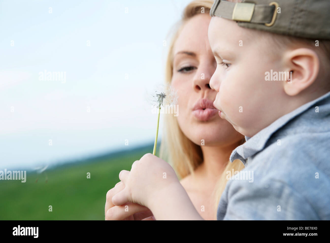 Young mother with her son, blowing a dandelion clock Stock Photo