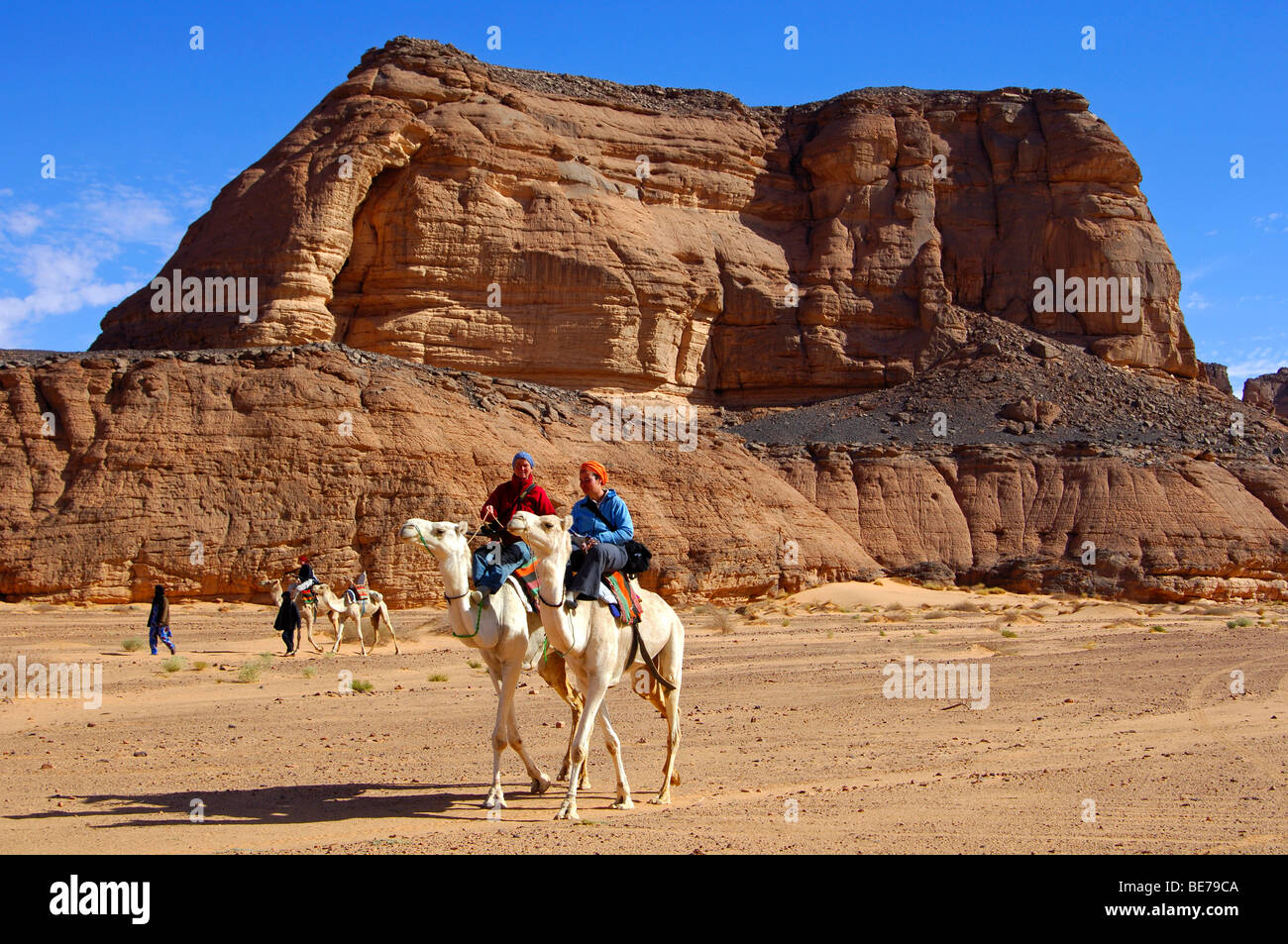 Tourists riding camels in the wadis of the Acacus mountains, Libya Stock Photo