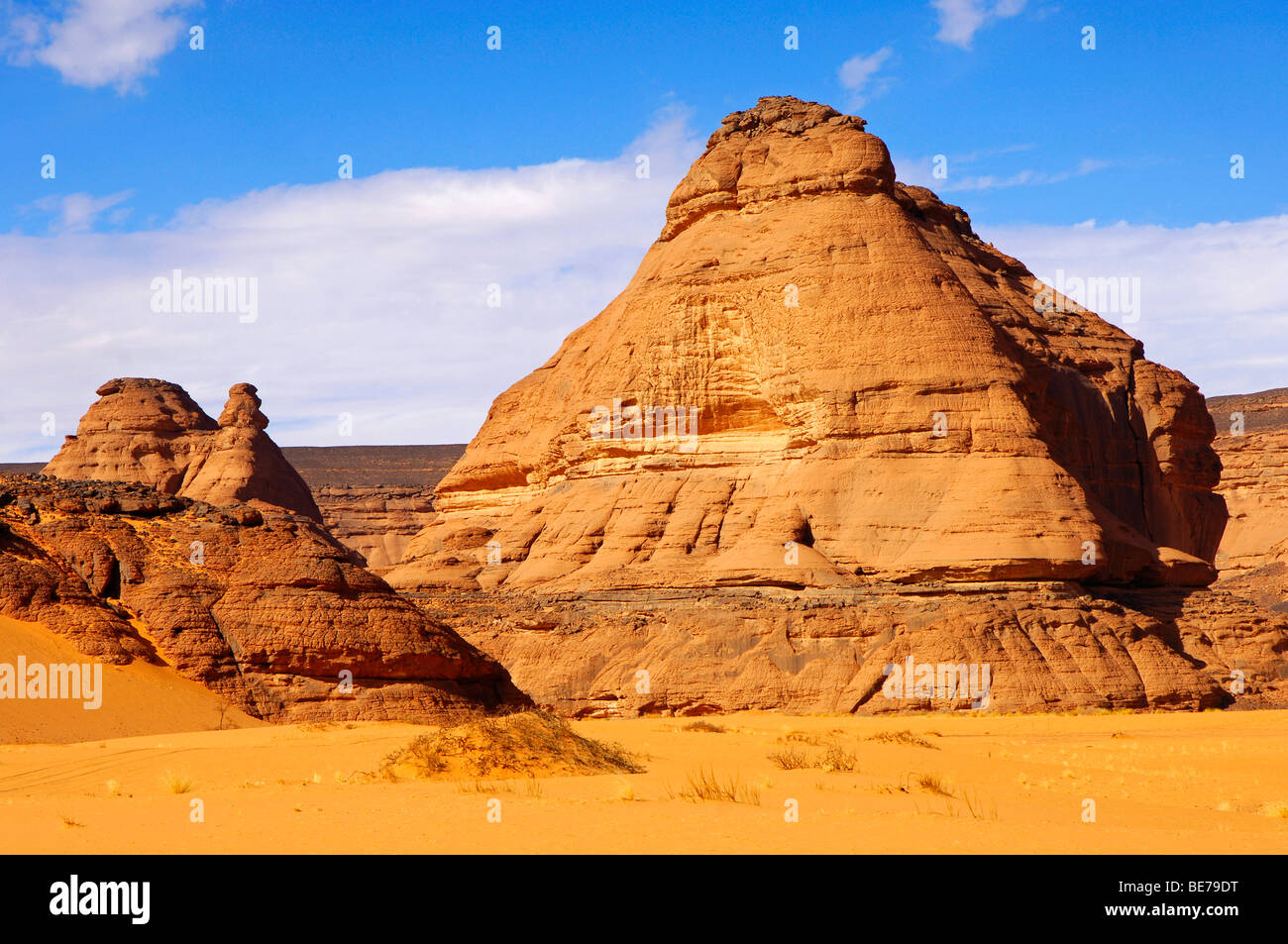 Desert sand and cone shaped rock formation made of sandstone in the Acacus mountains, Libya Stock Photo