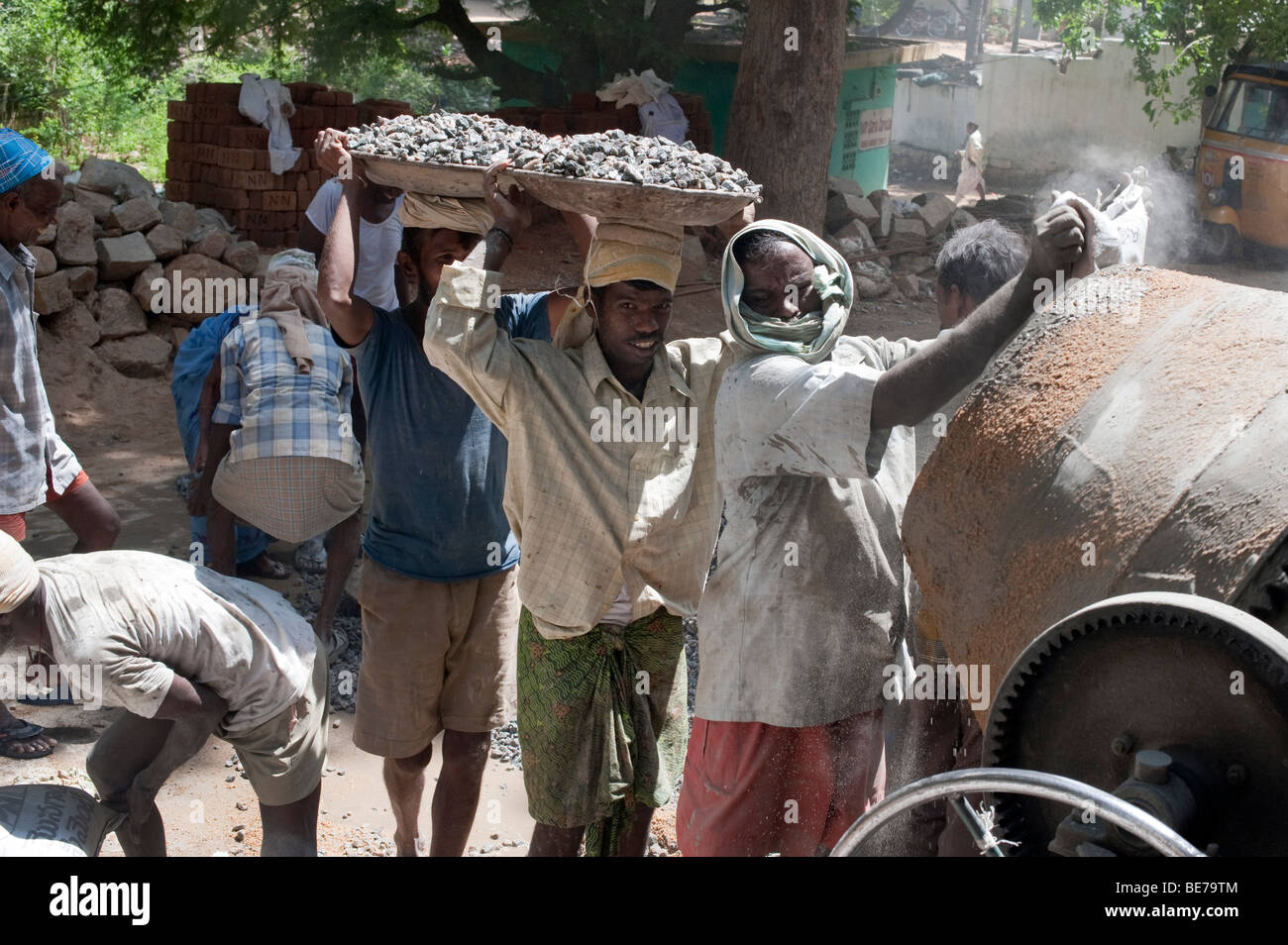 Indian construction workers mixing rock sand and cement to make