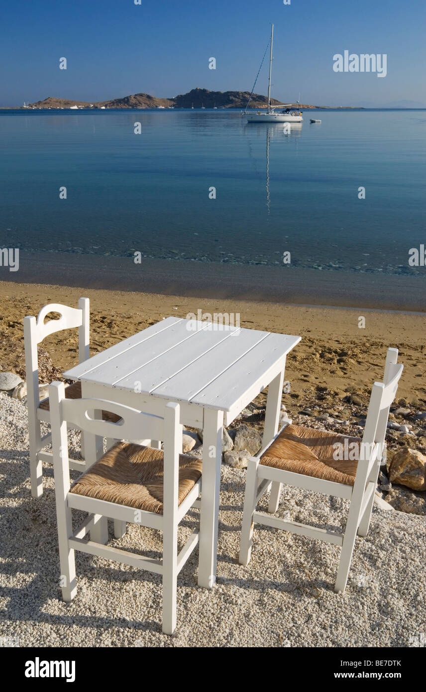 Table and chairs on a beach, Naoussa, Paros, Greece Stock Photo