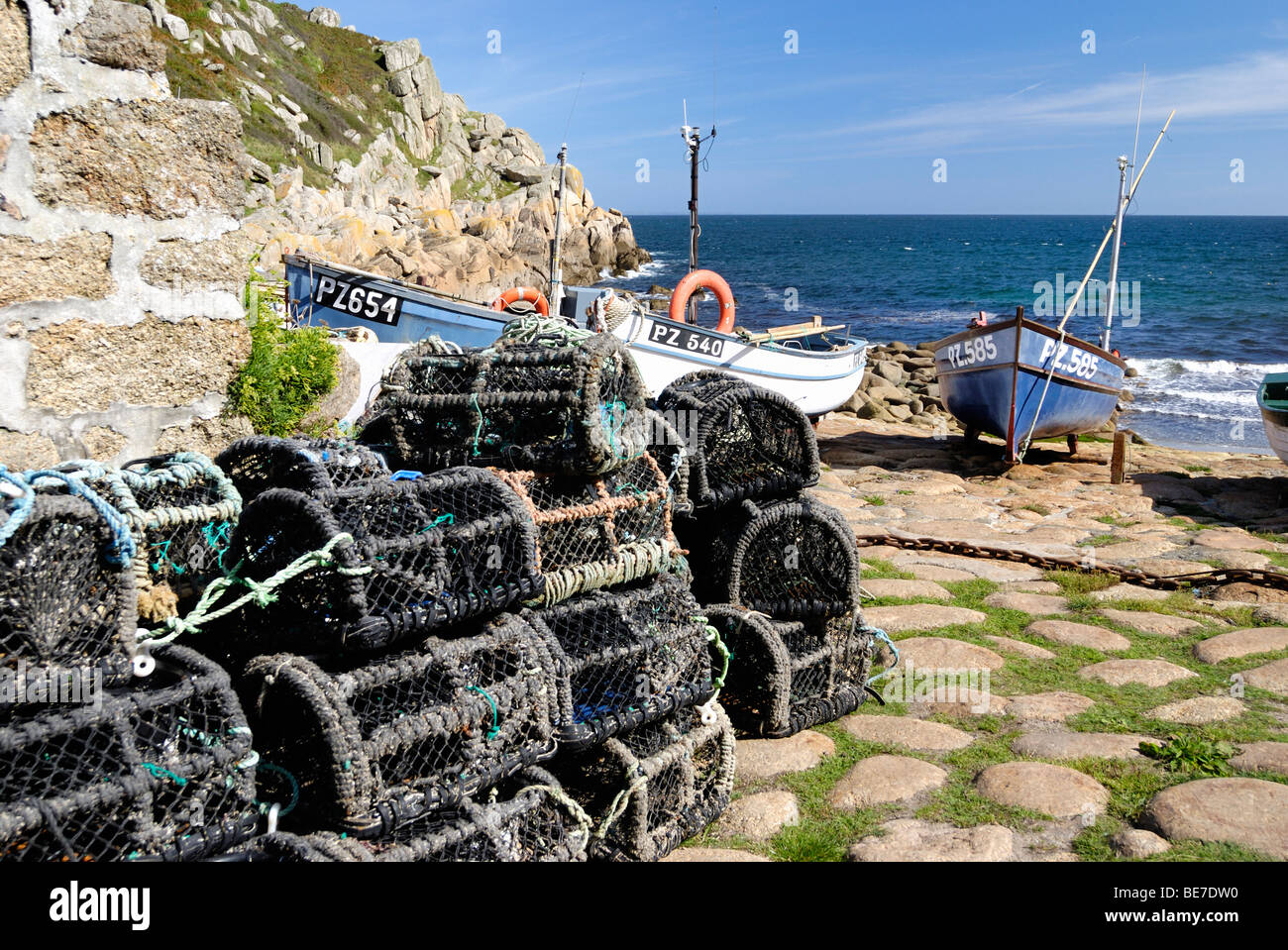 Lobster baskets on a quay with fishing boats in the background Stock