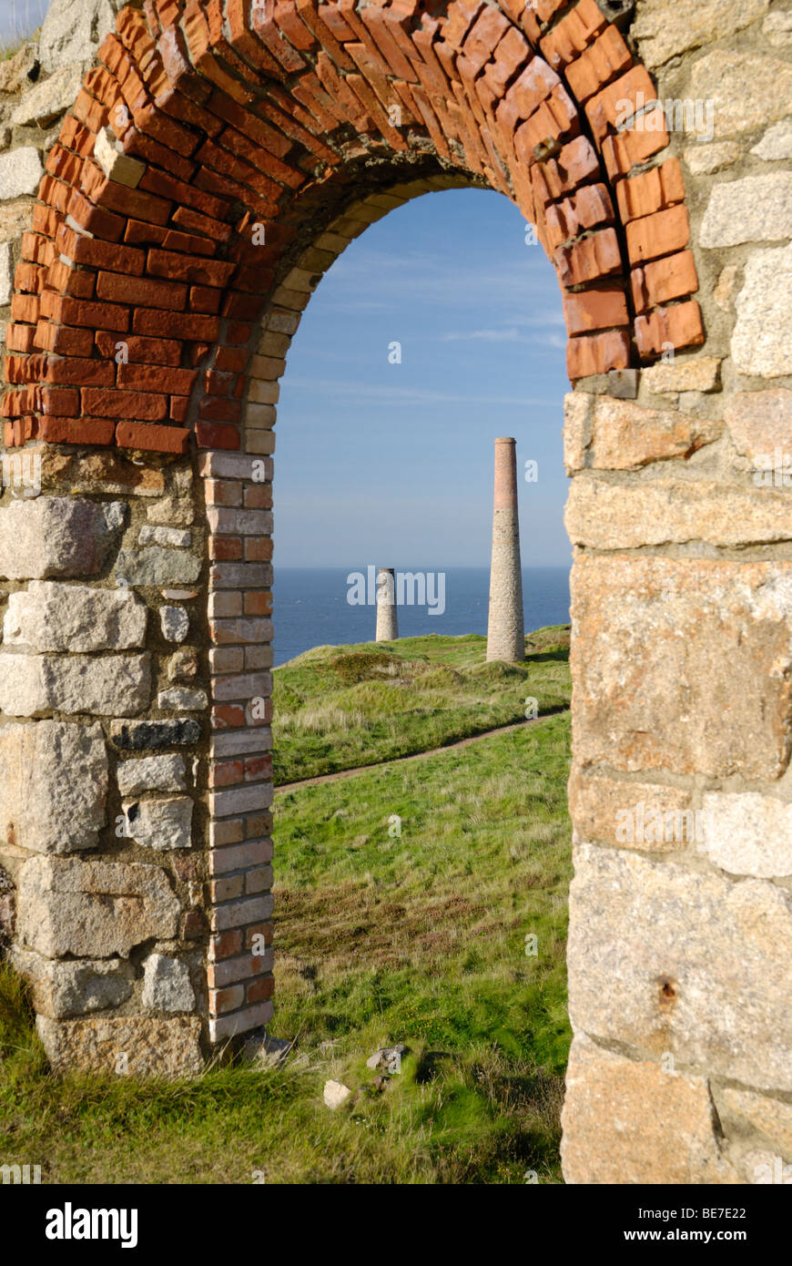 Two Cornish tin mine chimneys as seen through the ruins of a mine Stock Photo