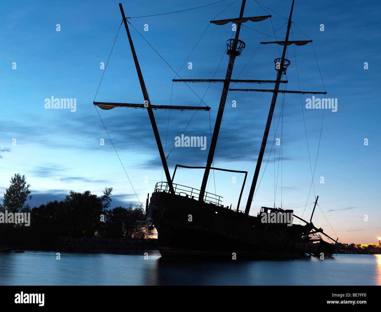 Grounded tall ship silhouette against twilight sky Stock Photo