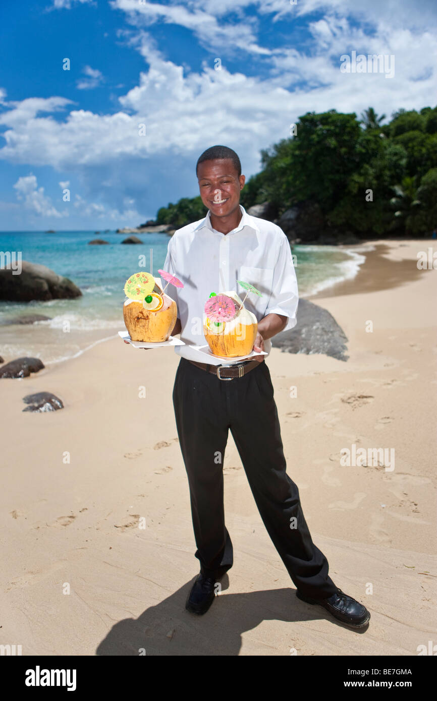 A waiter holding two decorated coconuts filled with drinks, island Mahe, Seychelles, Indian Ocean, Africa Stock Photo