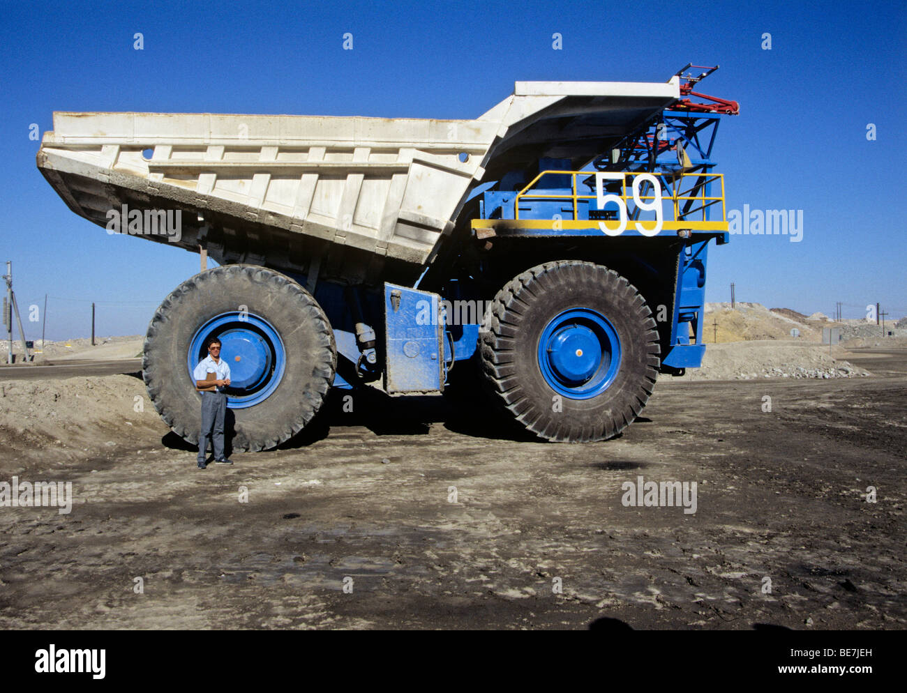 man in front of huge wheel of mining dump truck - uranium mine of rossing - namibia Stock Photo