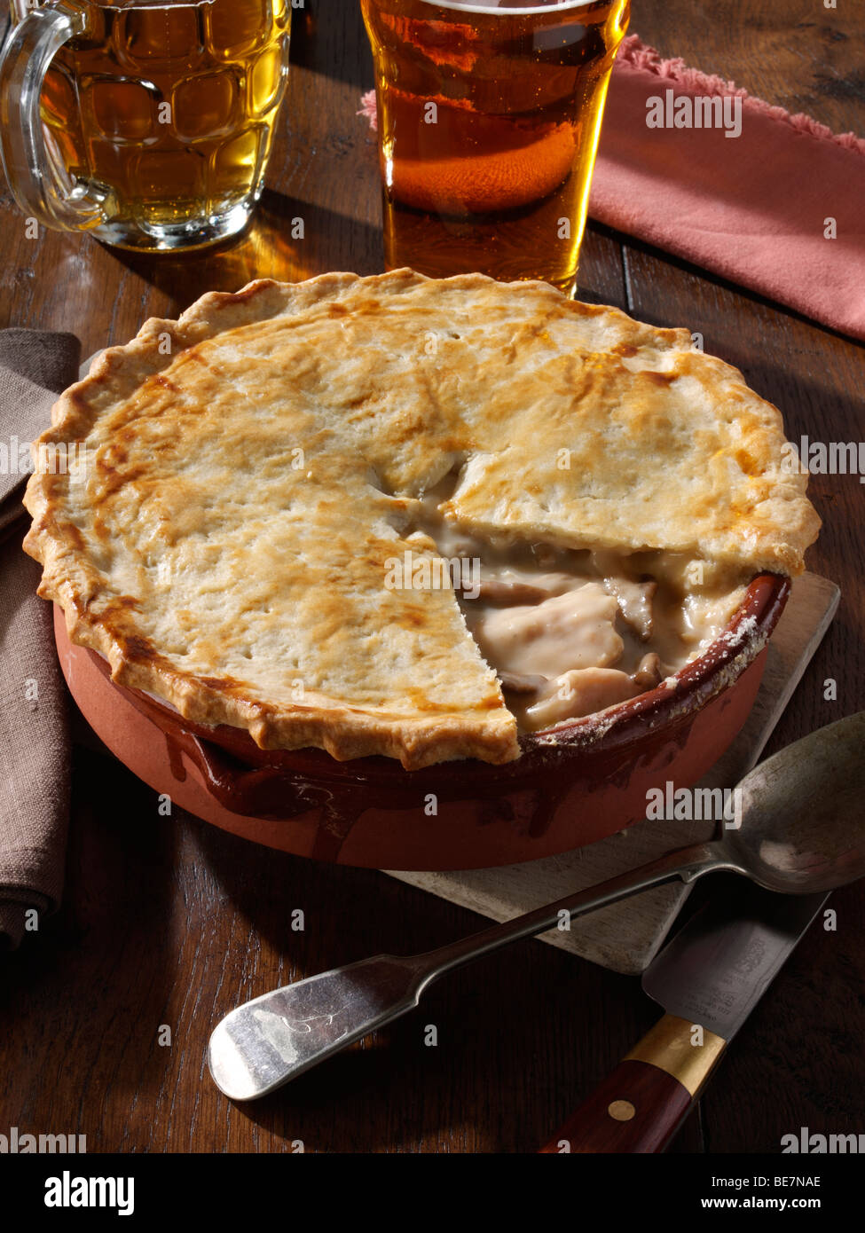 Whole family size chicken pie with runner beans and beer in a table setting Stock Photo