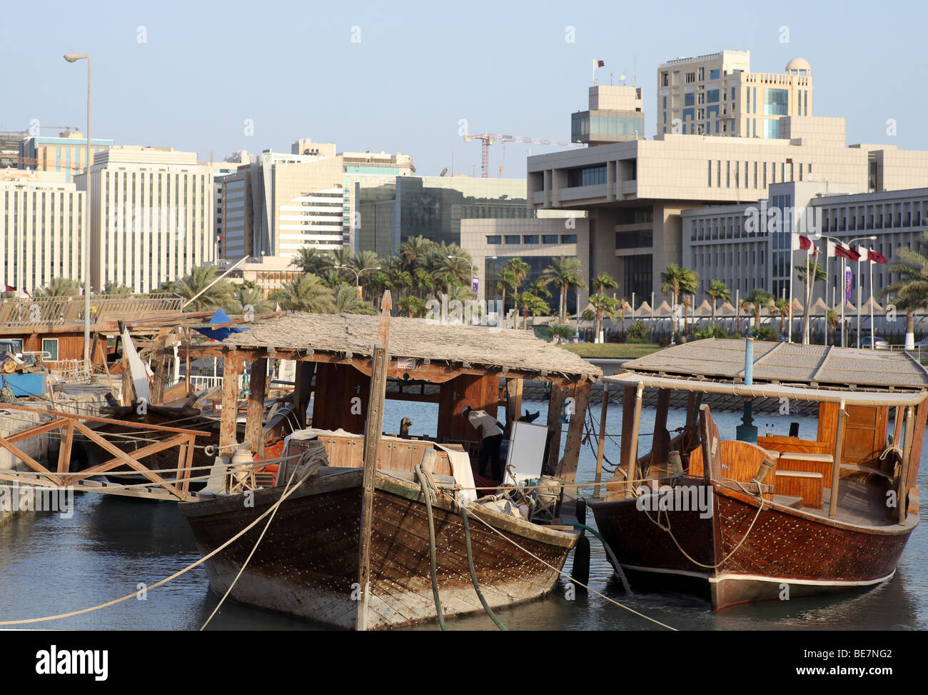 Working dhows moored at the harbour on Doha's Corniche, in Qatar, Arabia. In the background are buildings  from the 60s and 70s. Stock Photo
