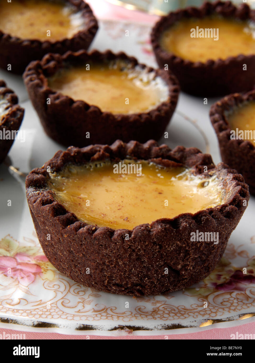 Chocolate custard tarts on an antique plate in a table setting Stock Photo