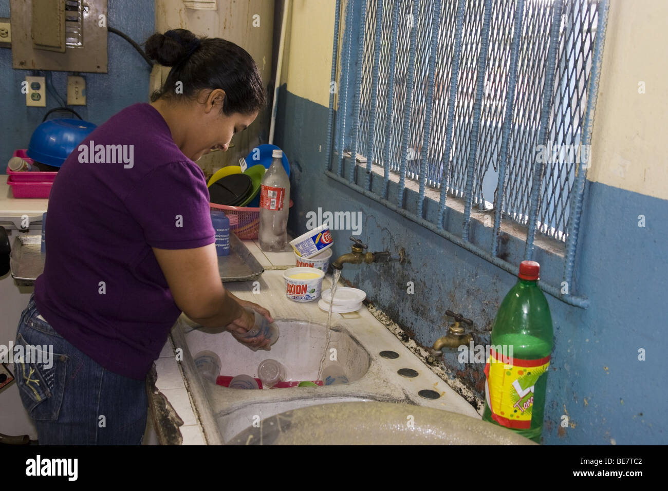 Woman washing the dishes at a low income school area in San Miguelito, Panama City, Republic of Panama, Central America Stock Photo