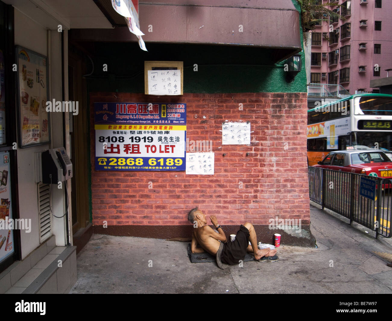 Hong Kong. Tramp  on Caine Road, a typical busy middleclass neighbourhood  On the wall ads from a property agent. Stock Photo