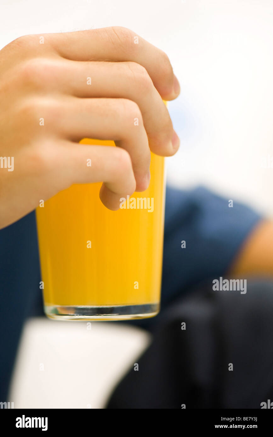 Person holding glass of orange juice, cropped Stock Photo