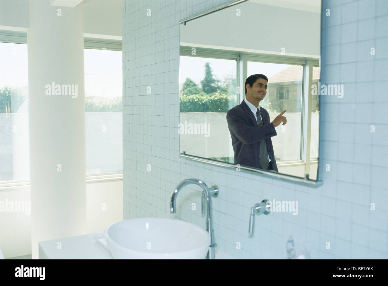 Businessman in bathroom having conversation with person out of frame Stock Photo