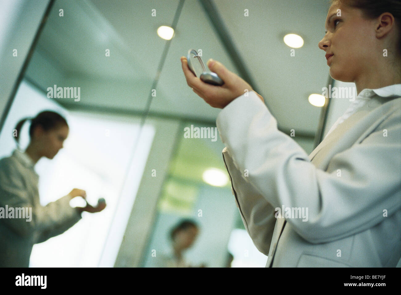 Woman holding powder compact putting on makeup, low angle view Stock ...