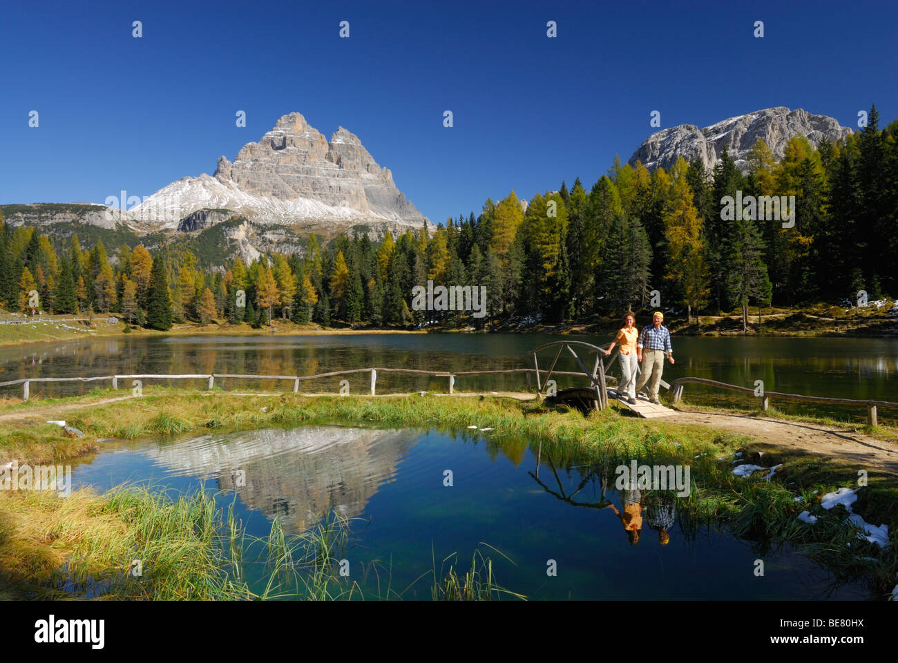 Drei Zinnen above lake Antornosee with couple on path with bridge, Dolomites, South Tyrol, Italy Stock Photo
