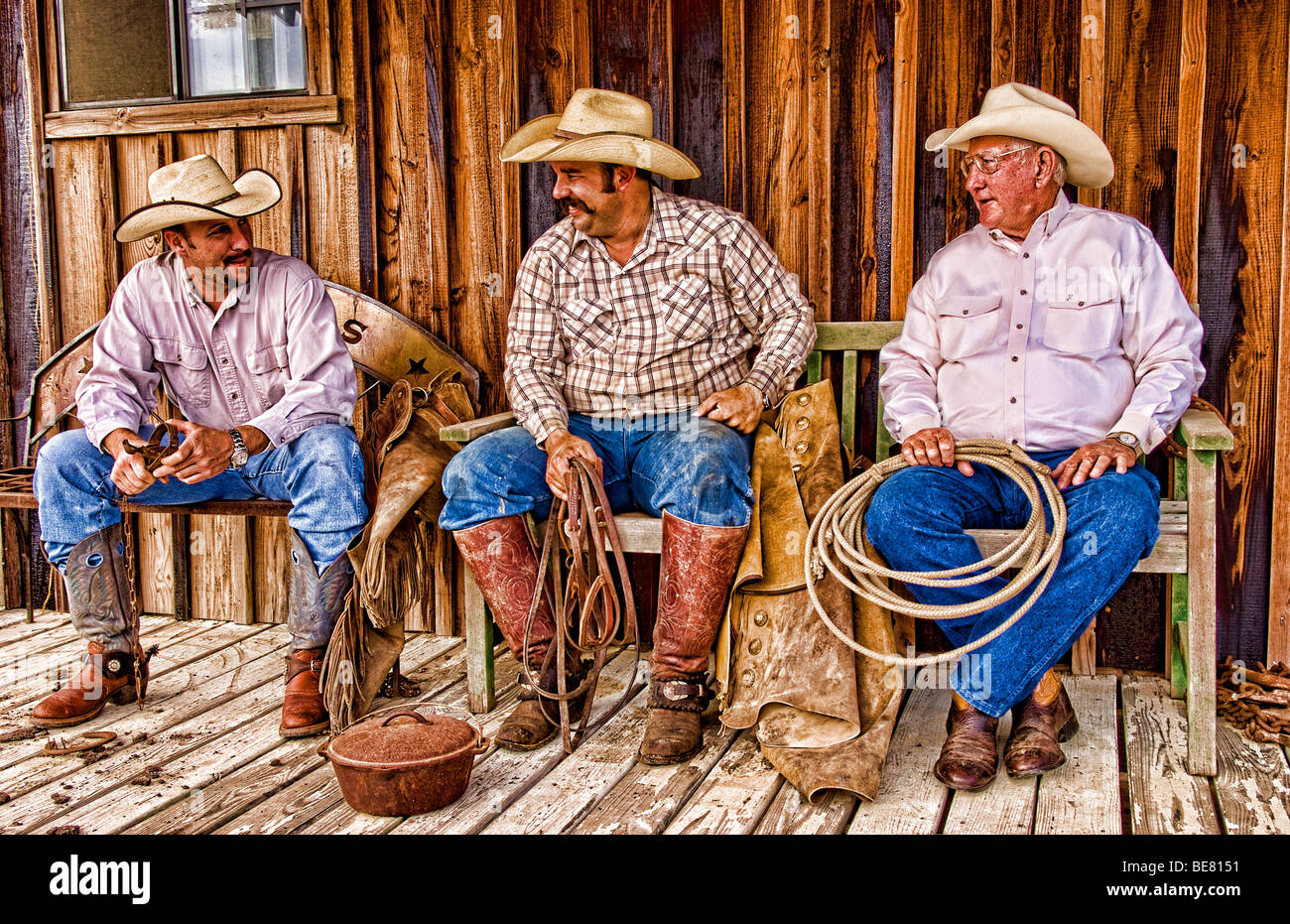 The cowboy life in the USA West as cowboys relax and talk on old porch at the ranch Stock Photo