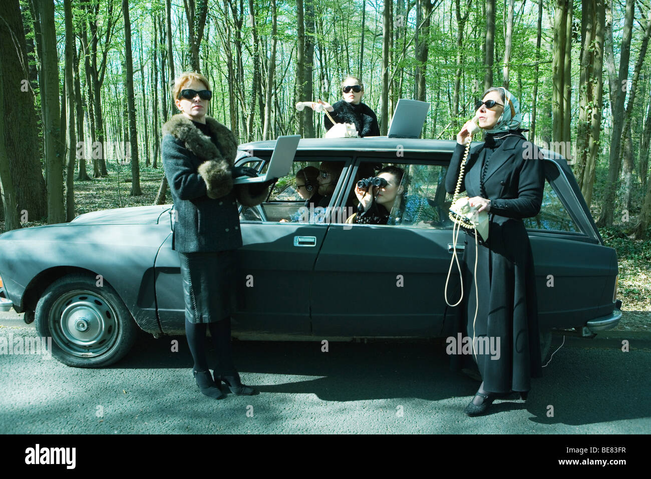 Group of spies with car parked in wooded area conducting surveillance Stock Photo