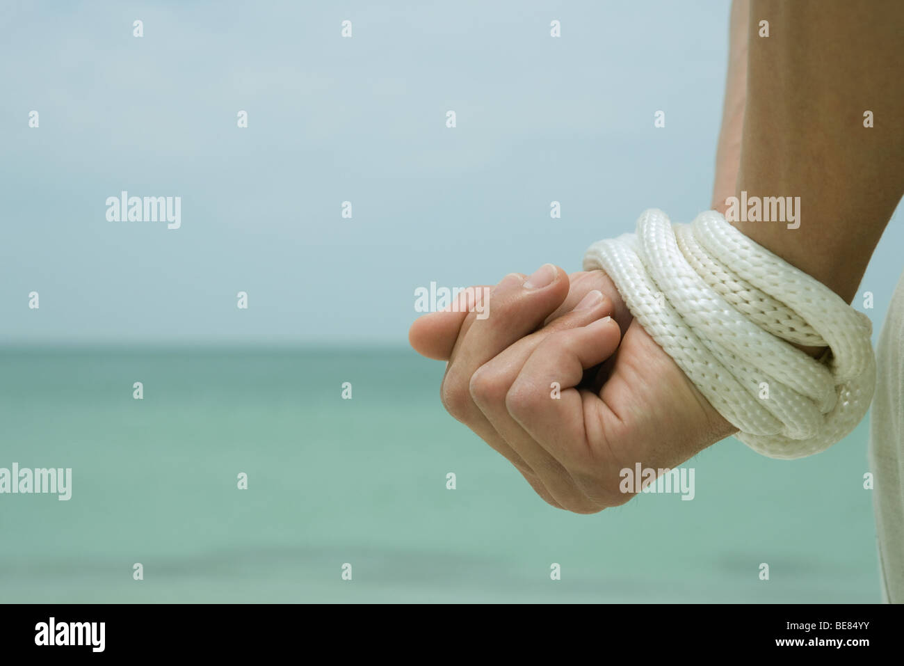 Man's hands bound with rope, cropped view, close-up Stock Photo