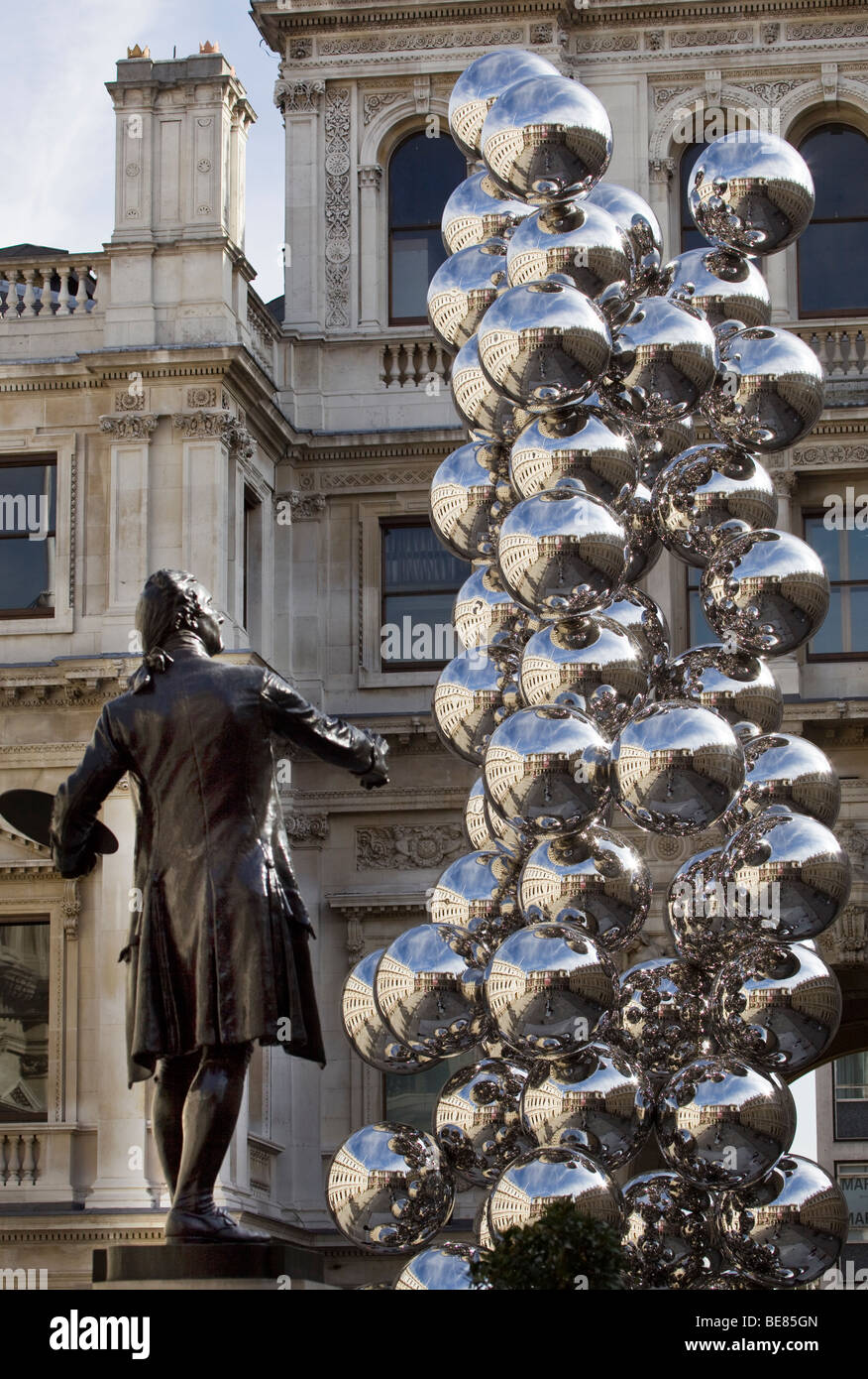 Anish Kapoor's Tall Tree and the Eye Sculpture and Staue of Sir Joshua Reynolds in the forecourt of the Royal Academy London Stock Photo