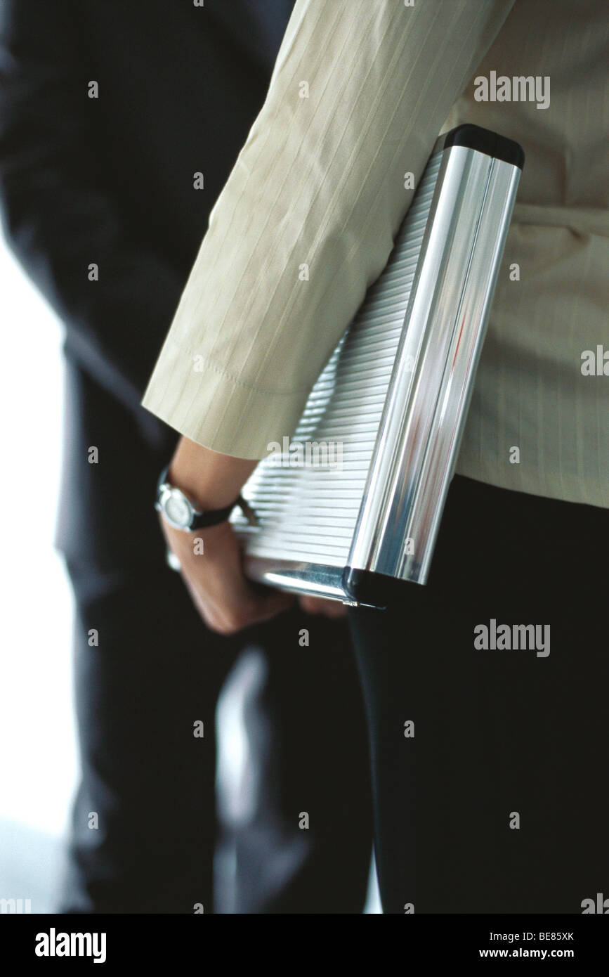 Businesswoman carrying briefcase under arm in conversation with colleague, mid section Stock Photo