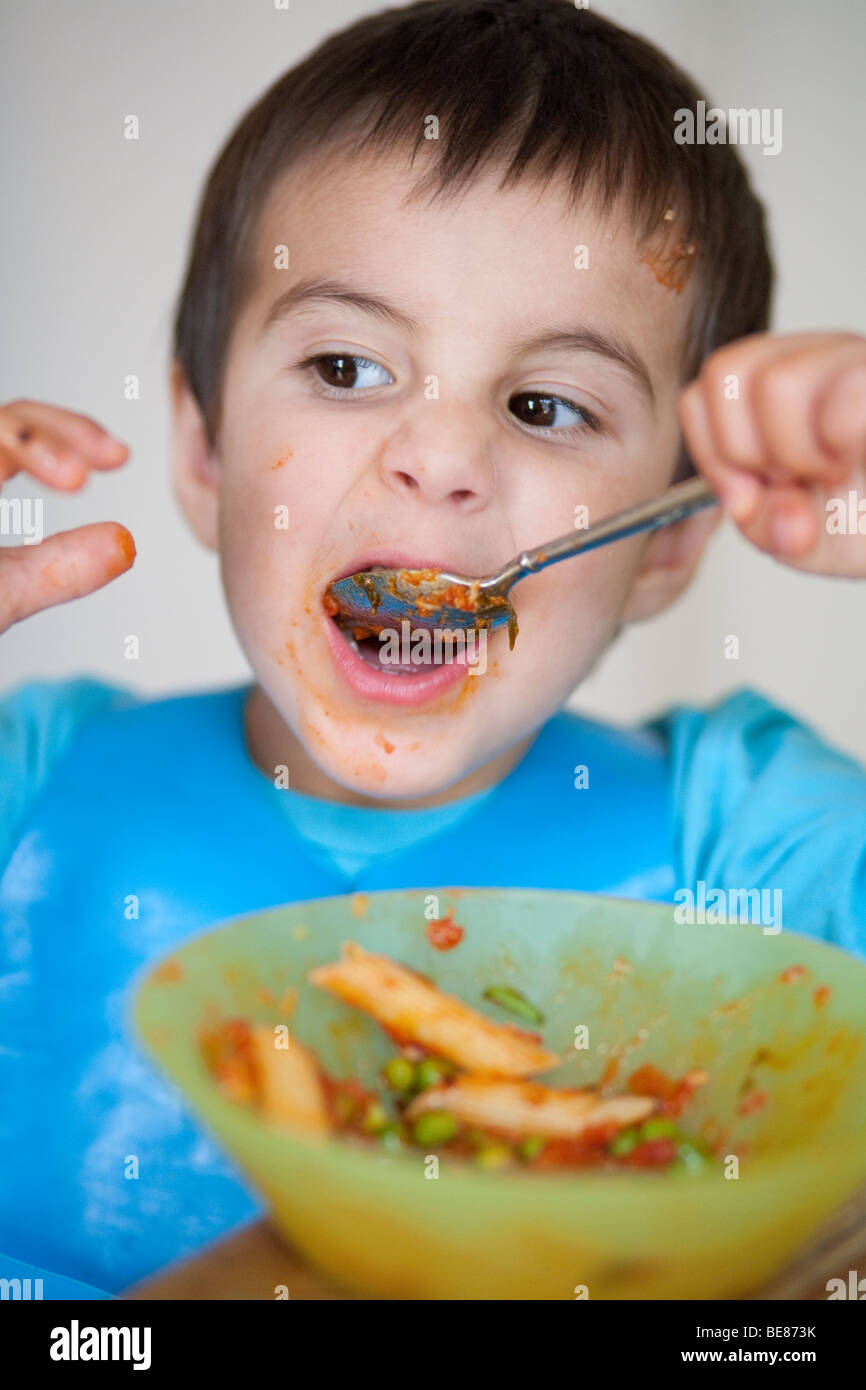 3 year old boy eating pasta with a spoon Stock Photo Alamy
