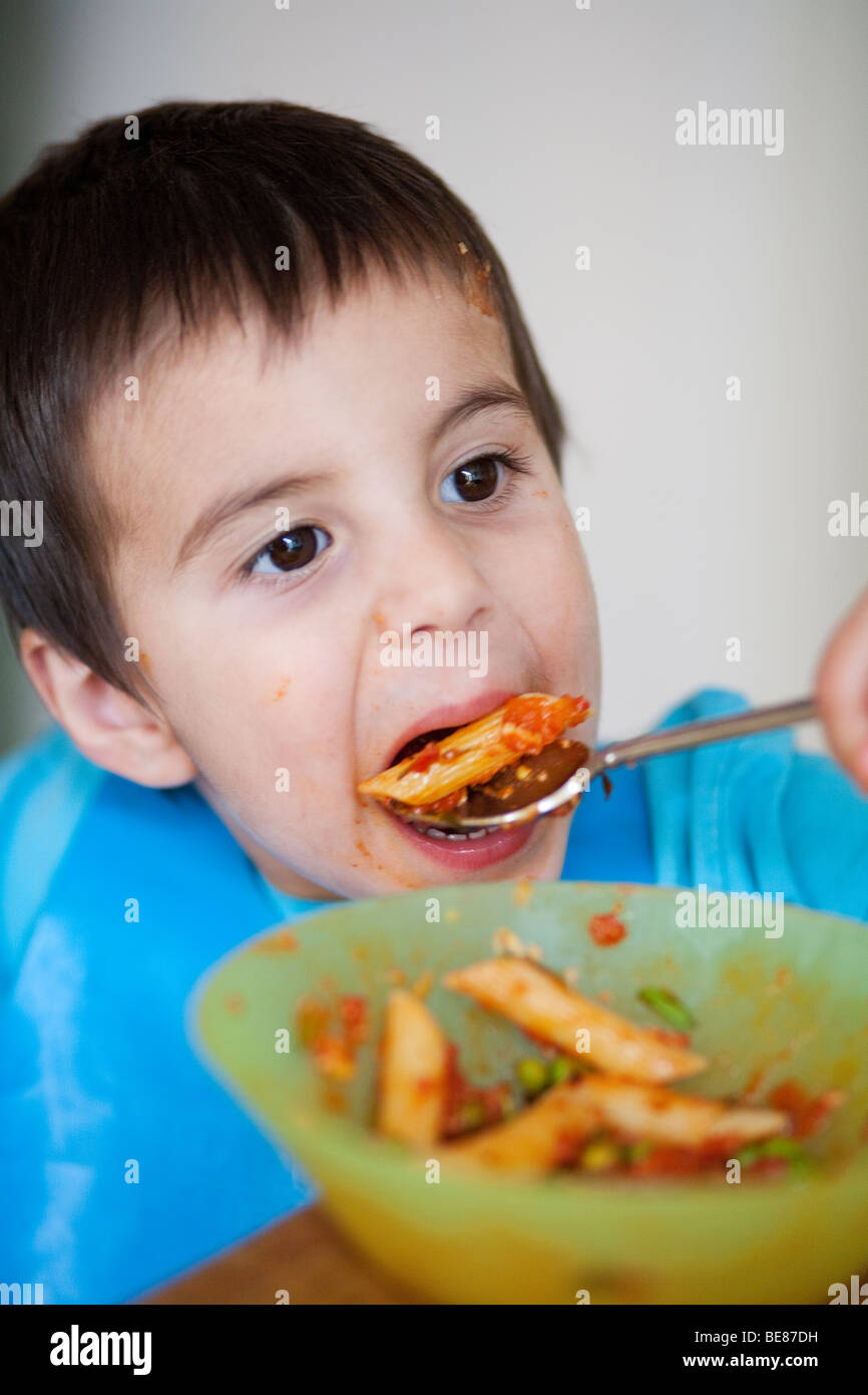 3 year old boy eating pasta with a spoon Stock Photo Alamy