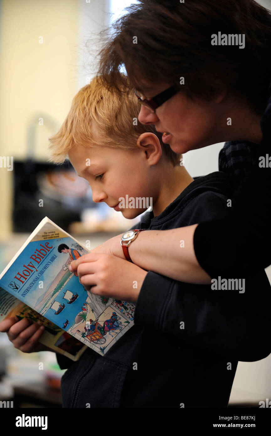 A TEACHER HELPS CHILDREN WITH A BIBLE READING AT A SUNDAY SCHOOL UK Stock Photo