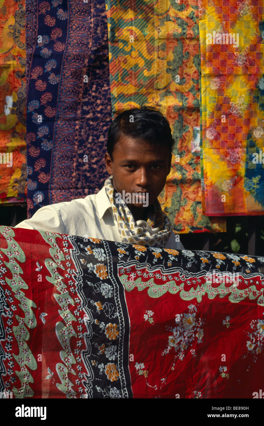 BANGLADESH Dhaka Fabric textile trader holding up printed cotton Stock
