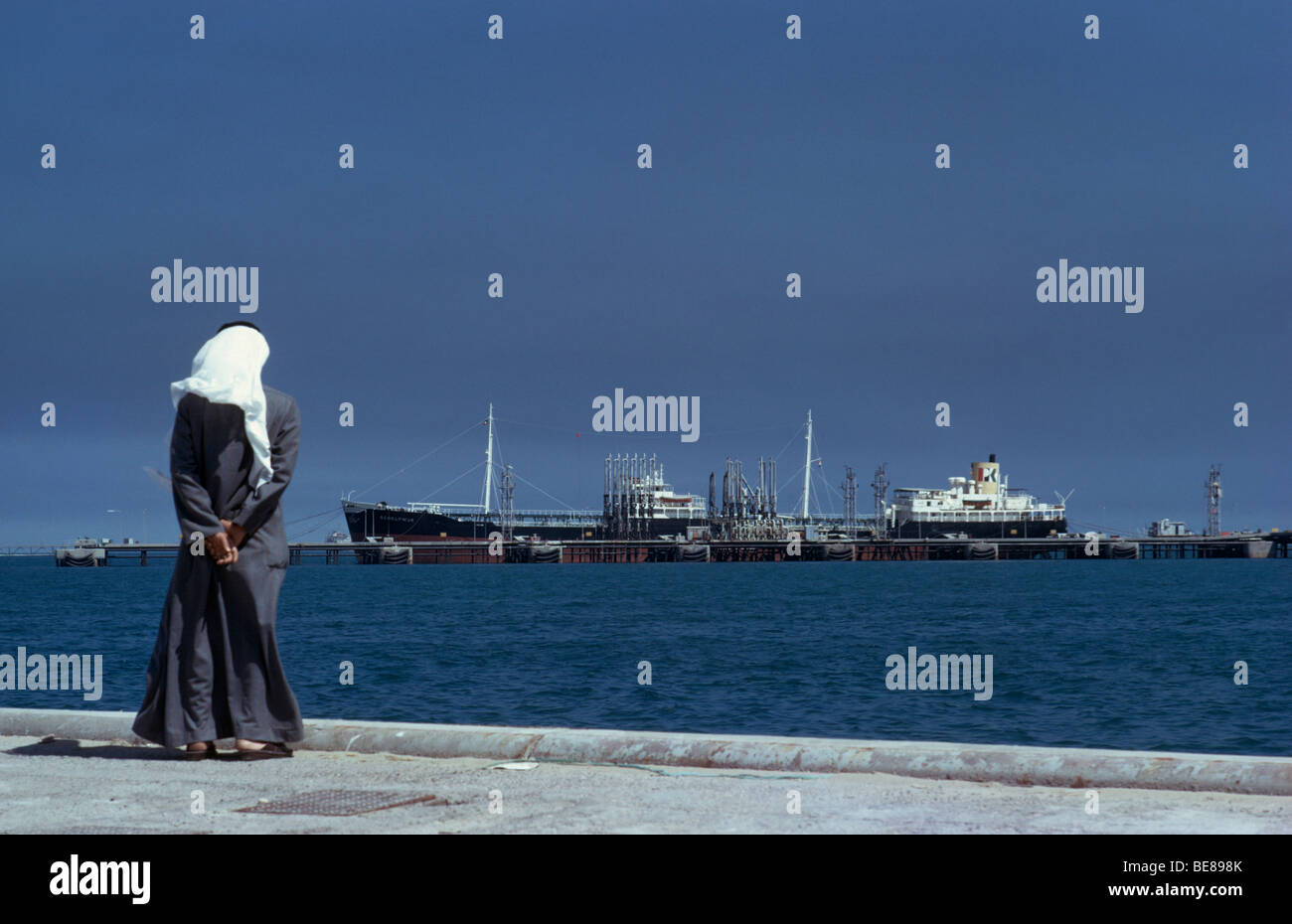 KUWAIT Middle East Gulf State Mina Ahmadi Arab man standing on docks looking at oil tanker at terminal Stock Photo