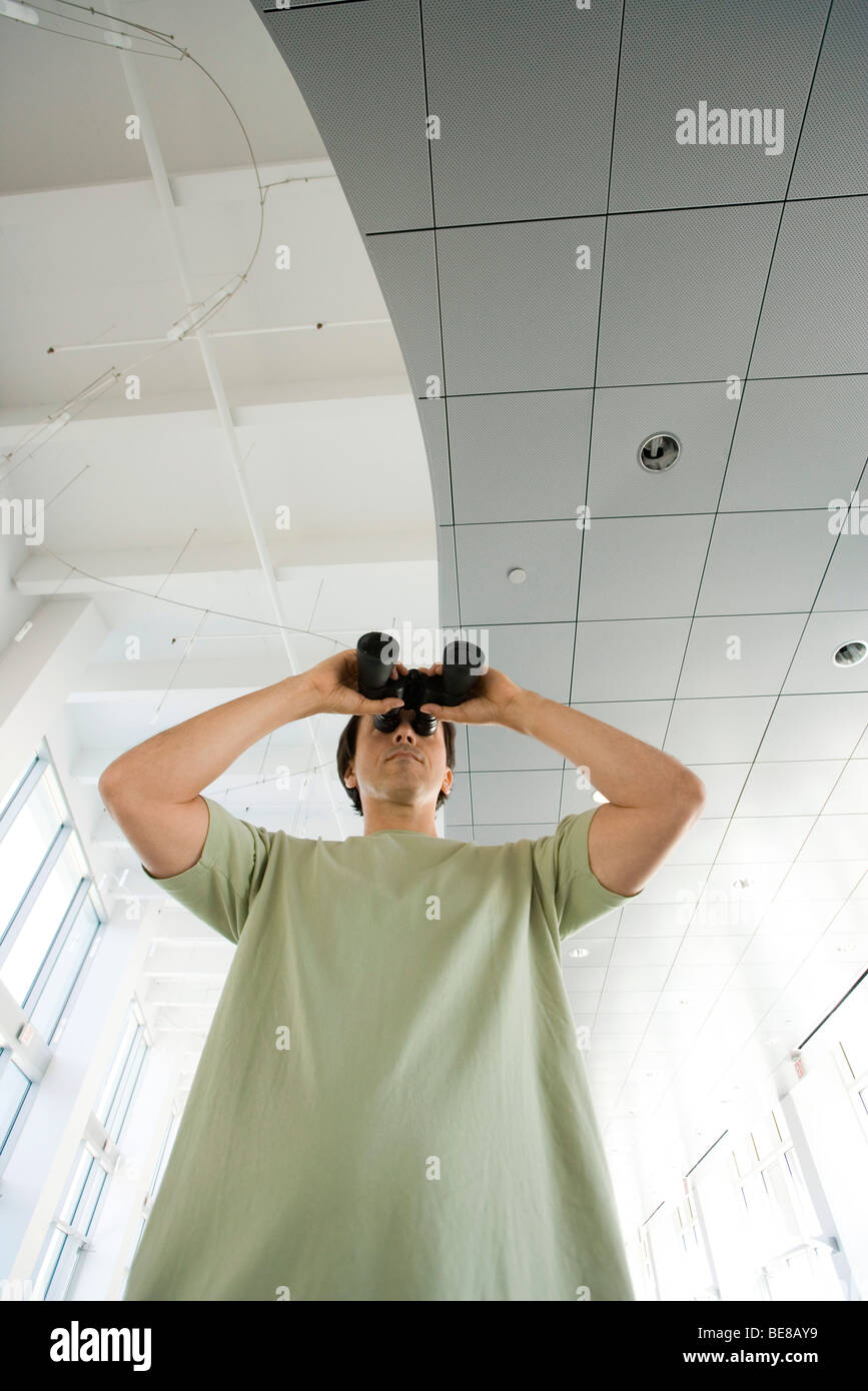Man looking through binoculars indoors, low angle view Stock Photo