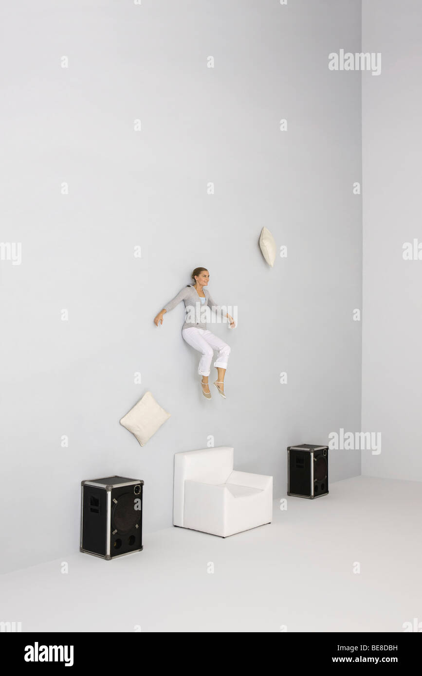 Woman floating in midair, listening to music through speakers Stock Photo