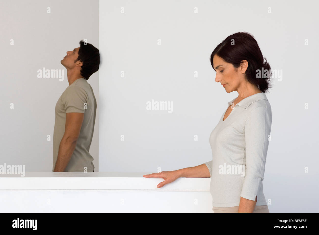 Woman with head lowered looking down, man in background looking away Stock Photo