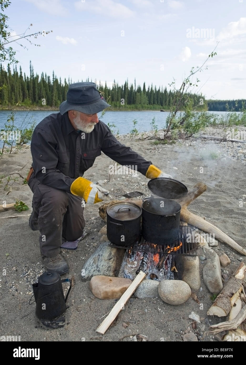Man cooking on a camp fire, pots, kettle, upper Liard River, Yukon Territory, Canada Stock Photo
