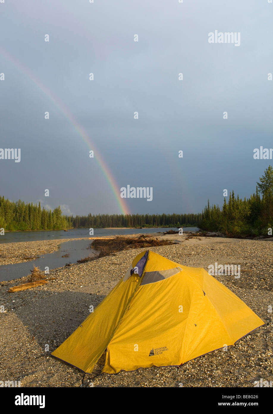 Tent on a gravel bar, rainbow behind, upper Liard River, Yukon Territory, Canada Stock Photo