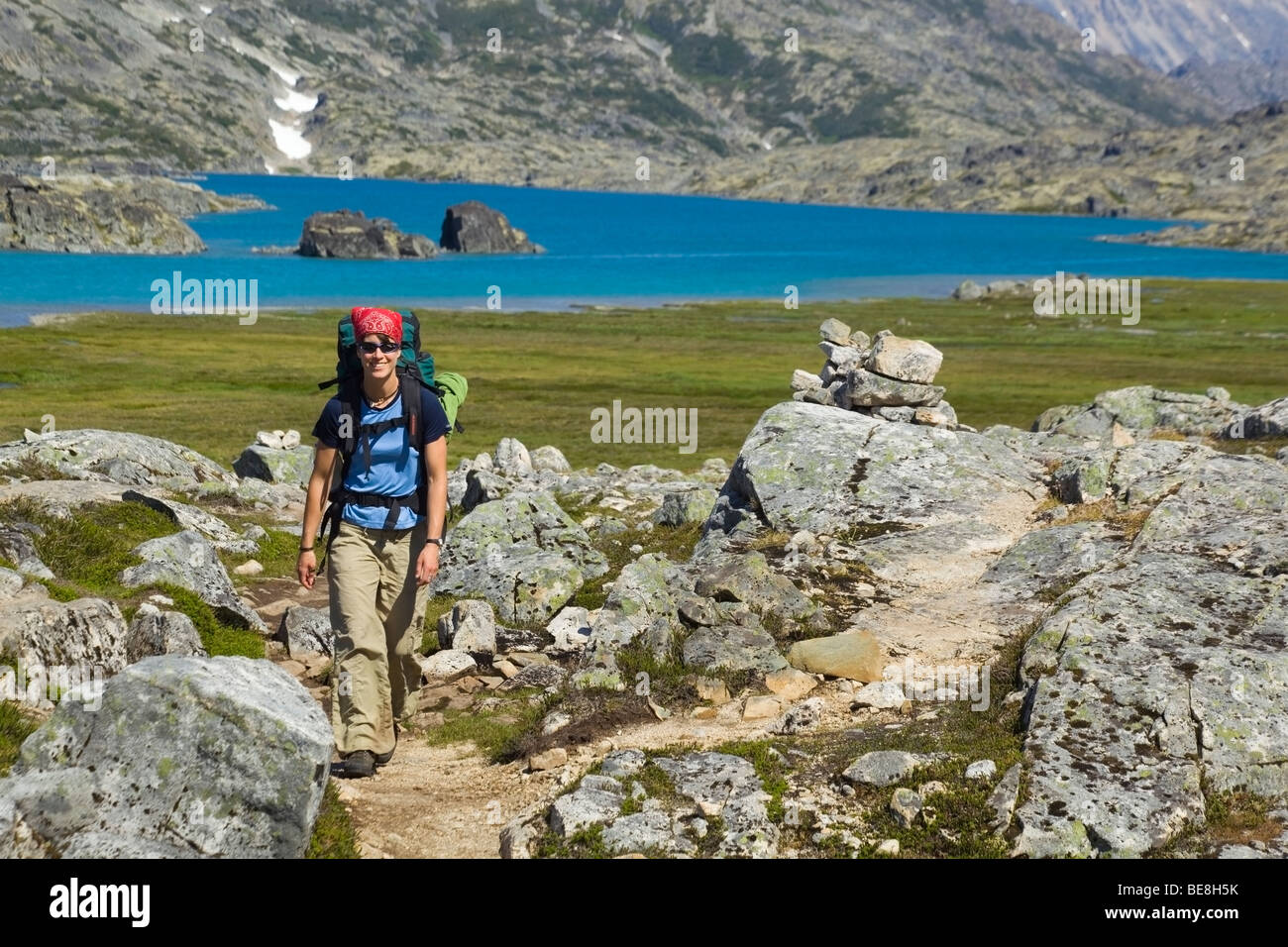 Young woman hiking, backpacking, hiker with backpack, historic Chilkoot Trail, Chilkoot Pass, Crater Lake behind, alpine tundra Stock Photo