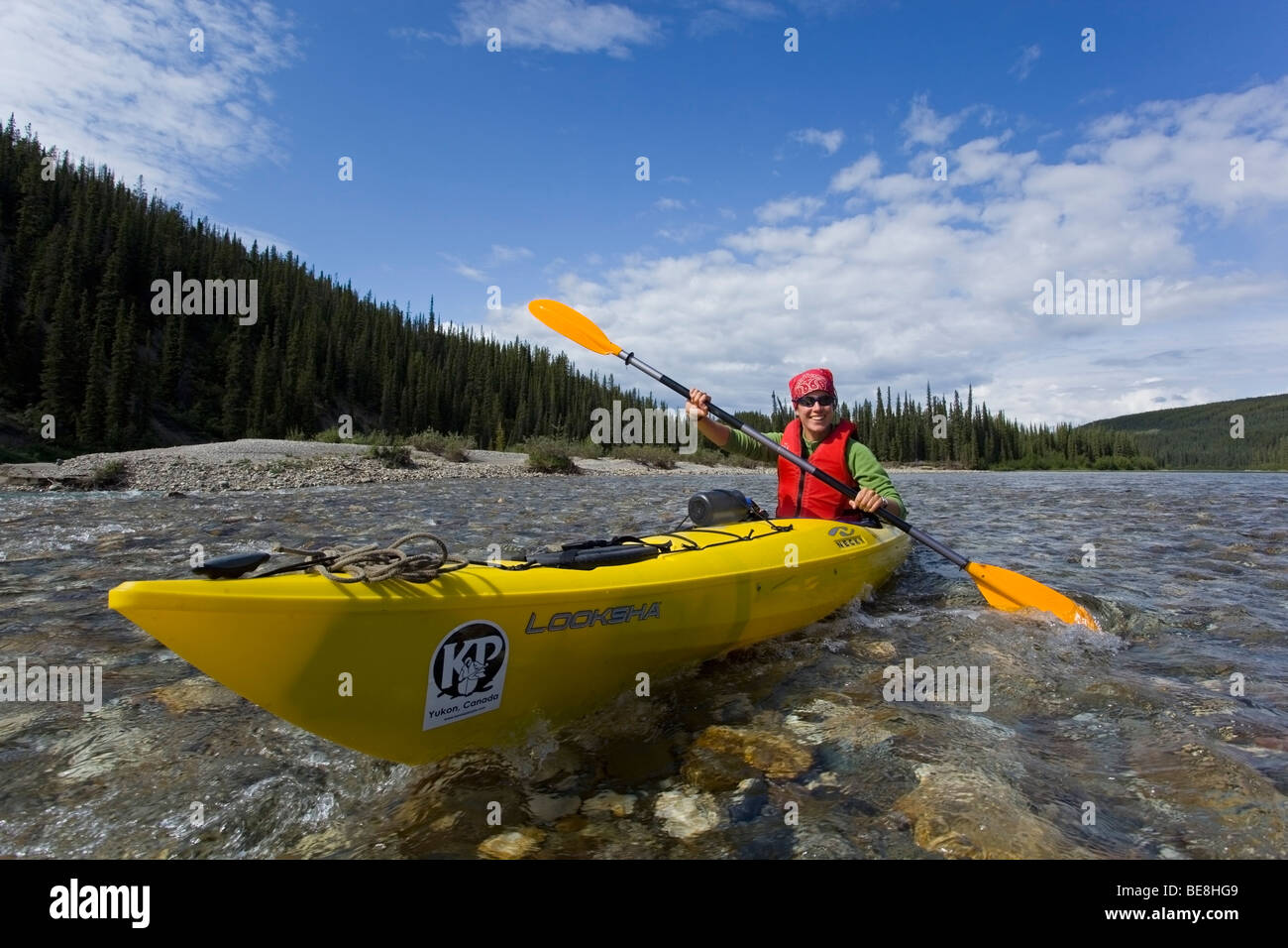 Young woman in kayak, paddling, kayaking, clear, shallow water of upper Liard River, Yukon Territory, Canada Stock Photo