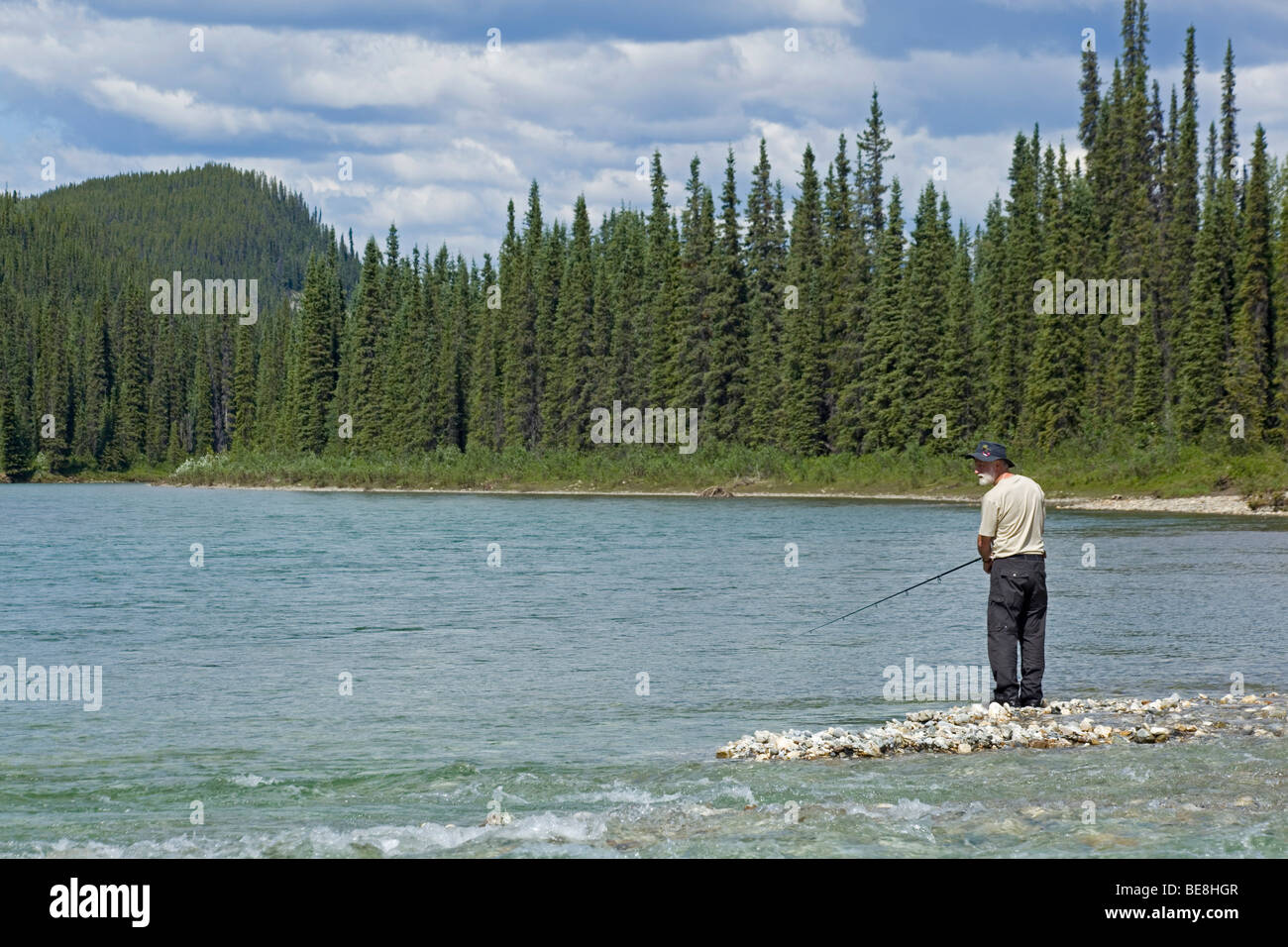 Man fishing on gravel bar, upper Liard River, Yukon Territory, Canada Stock Photo