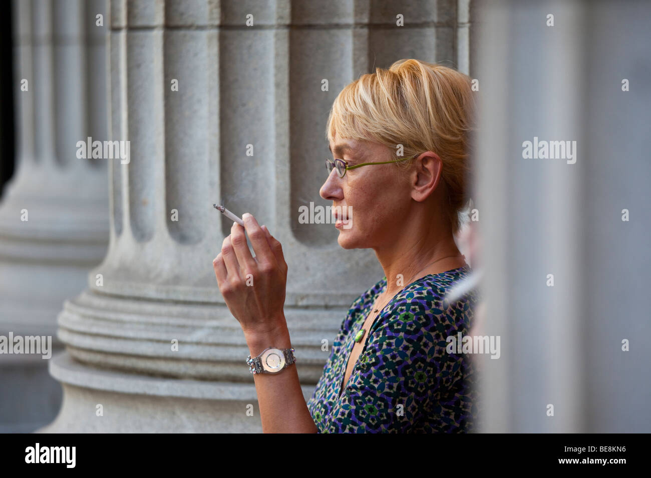 Woman smoking outside an office building in the Financial District in New York City Stock Photo