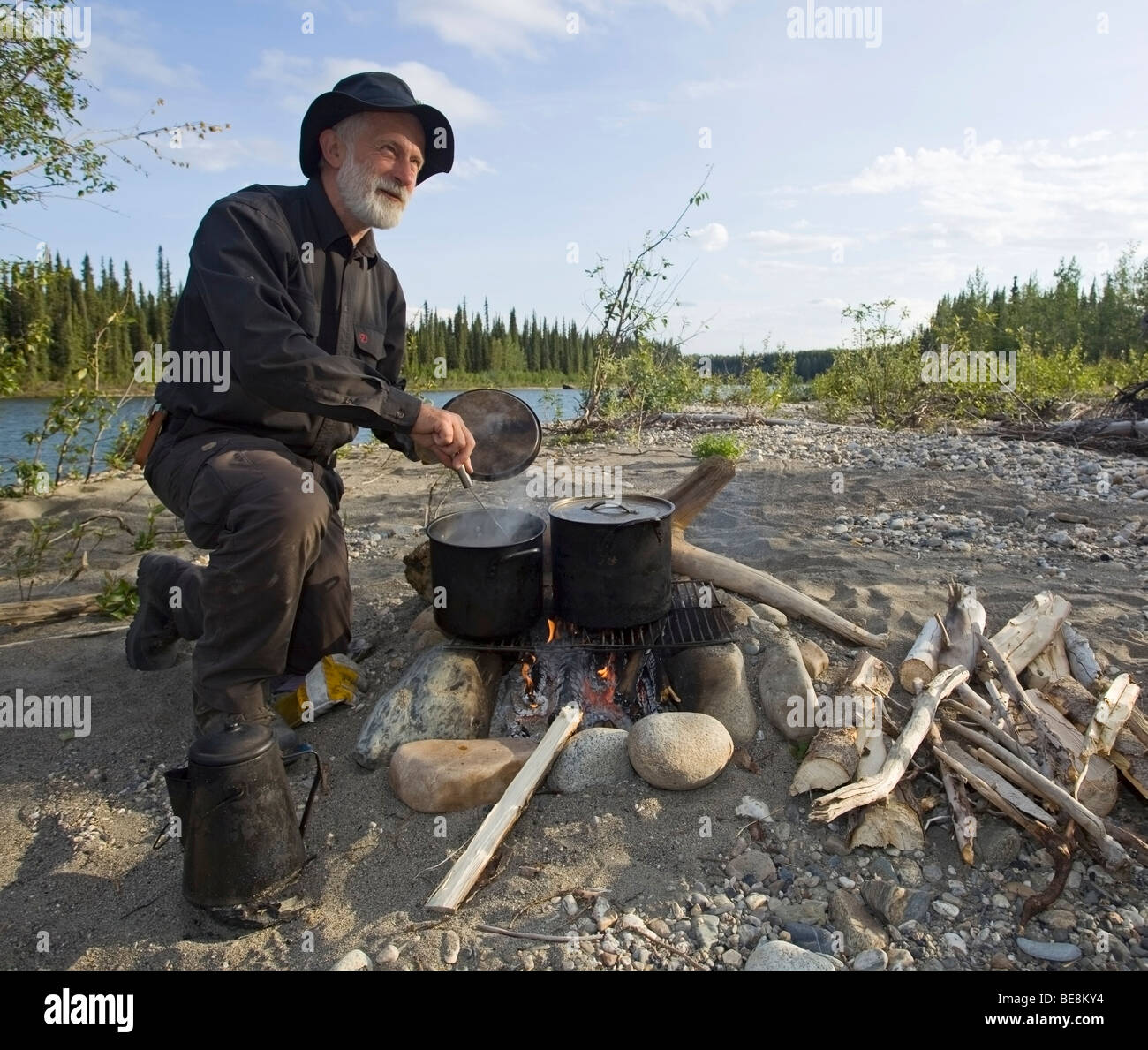 Man cooking on a camp fire, pots, kettle, upper Liard River, Yukon Territory, Canada Stock Photo