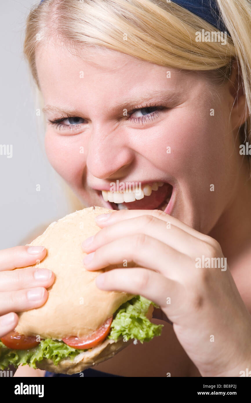 Young fat woman is eating fast food hamburger. Stock Photo