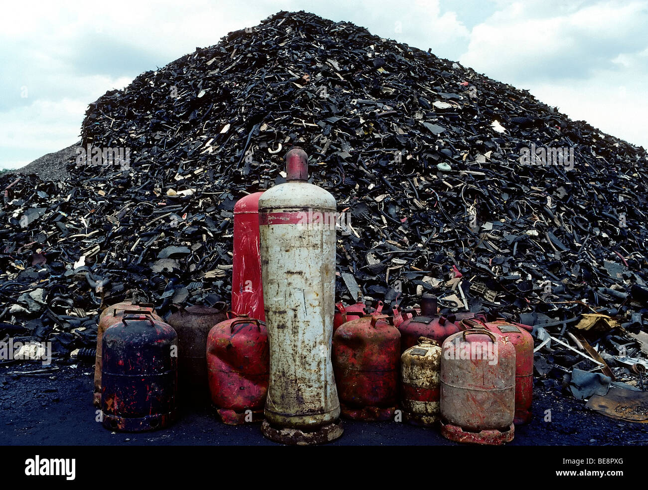 Mountain of shredded rubber waste and old gas cylinders, recycling