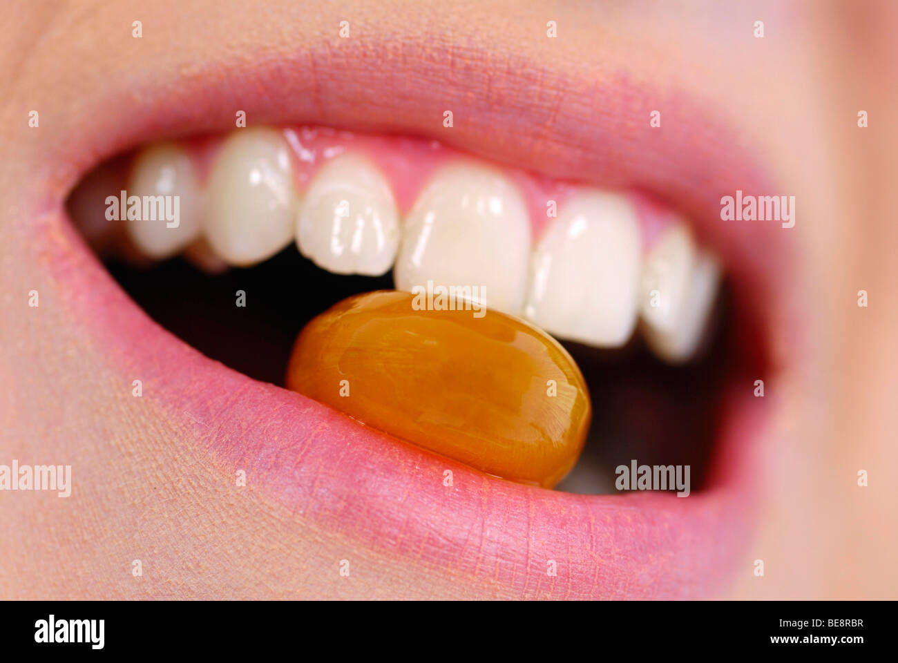 Mouth with teeth biting a bonbon Stock Photo