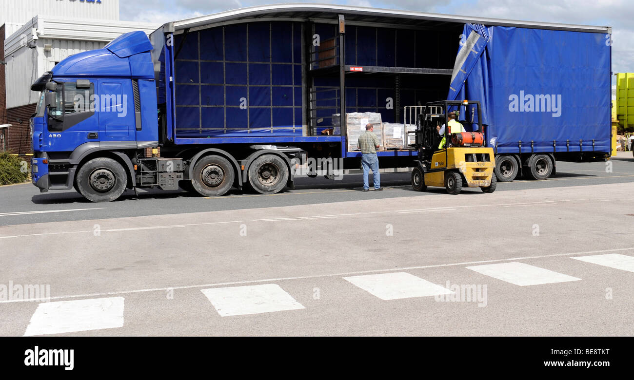 A forklift truck loads unloads a double deck curtainsided trailer and truck Stock Photo