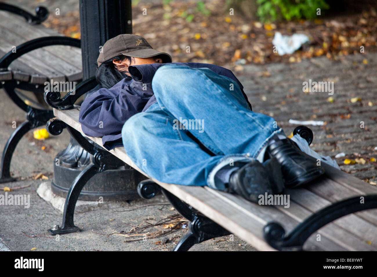 Homeless teenager sleeping on a park bench in Brooklyn New York Stock
