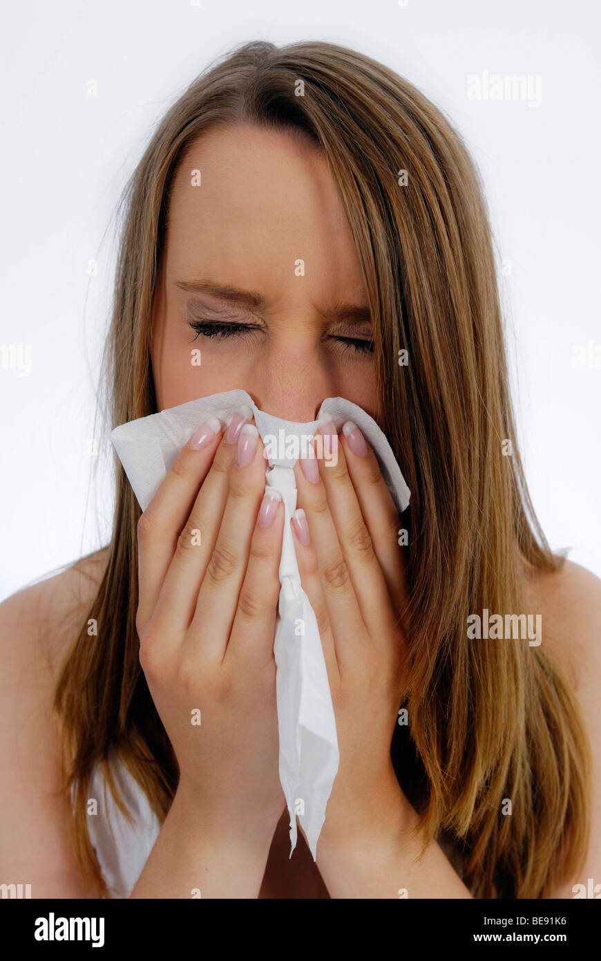Woman with a cold sneezing into a handkerchief Stock Photo