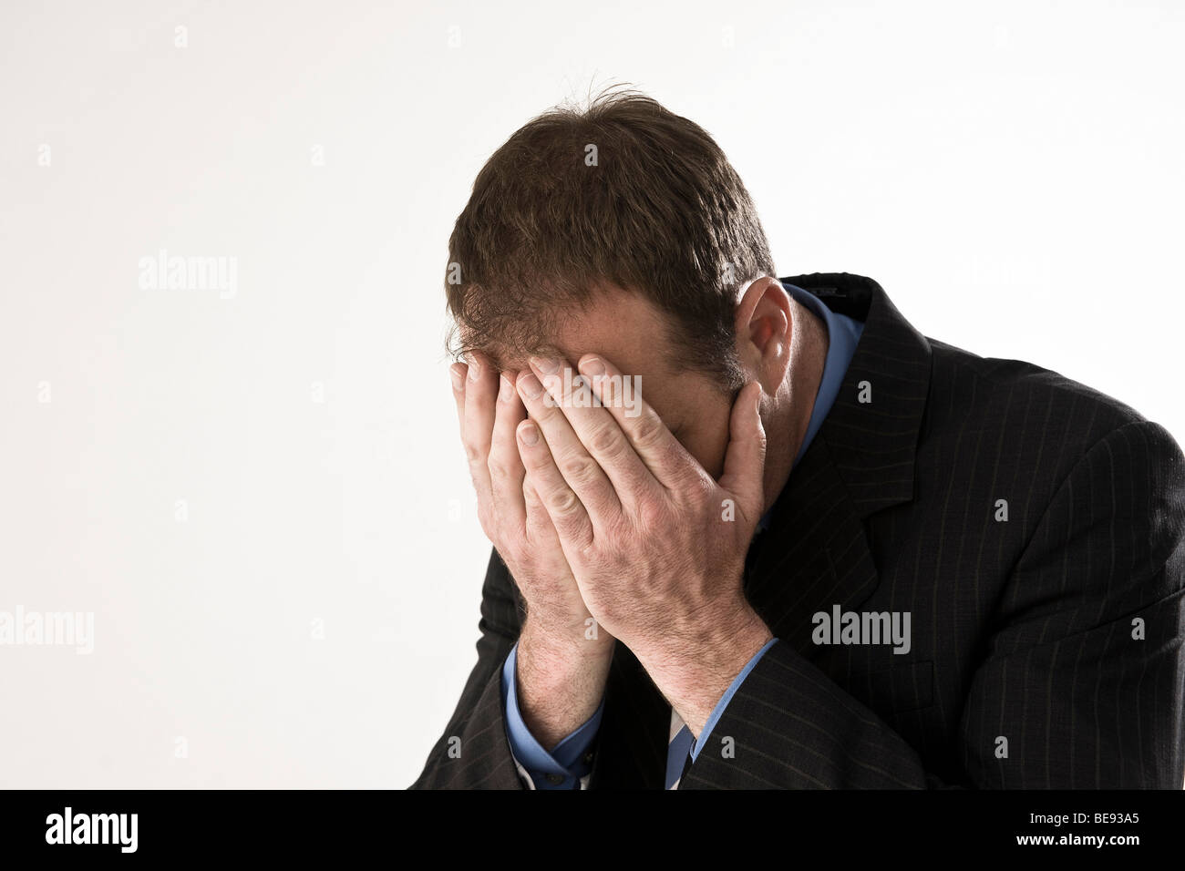 Man wearing a suit, hands covering his face Stock Photo