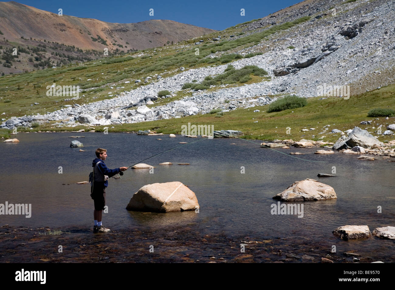 Young man fly fishing in stream near Greenstone and Conness Lakes, Inyo National Forest, California Stock Photo