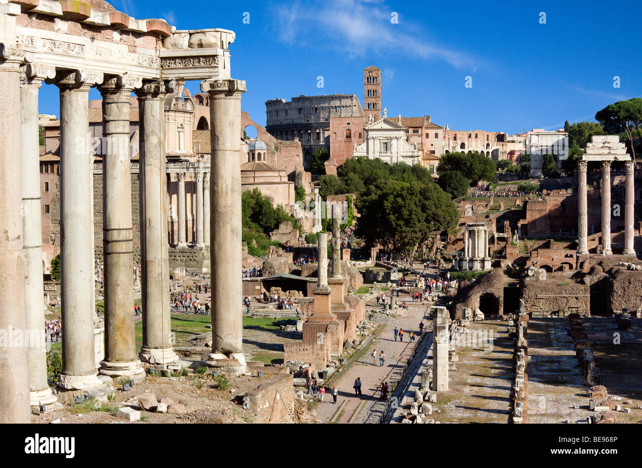 ITALY Rome Lazio Tourists in the Forum. Columns of Temple of Saturn in foreground and Colosseum in distance Stock Photo
