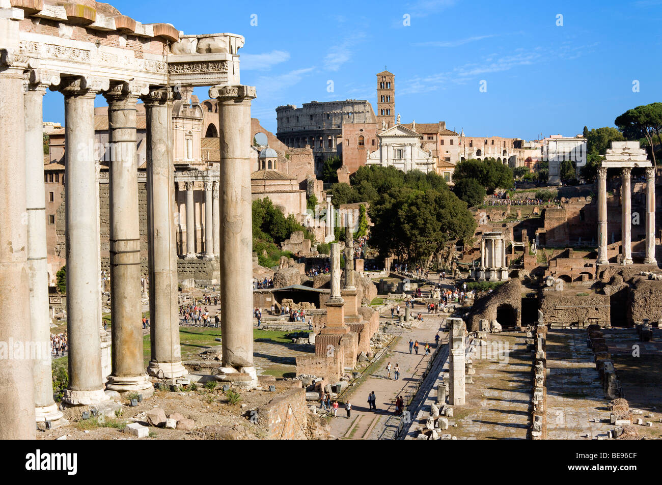 ITALY Rome Lazio Tourists in Forum. Columns of Temple of Saturn in foreground and Colosseum in distance Stock Photo